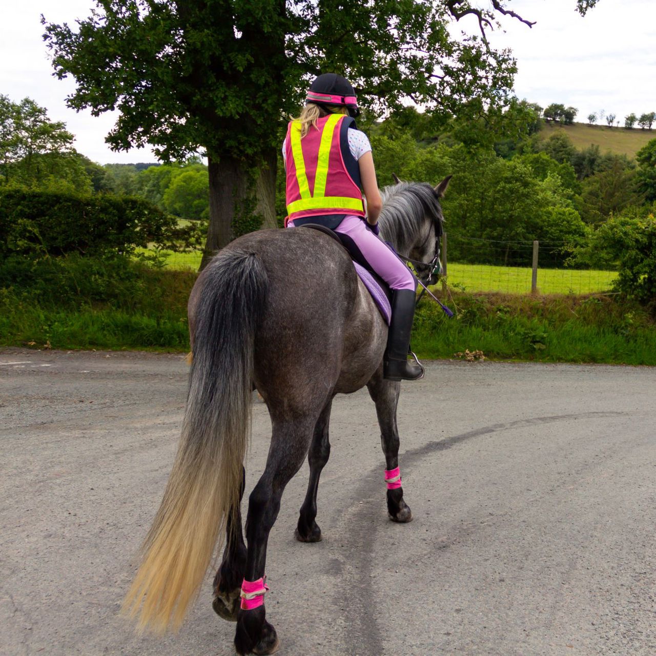 Horse rider wearing reflective safety wear on the road in the countryside