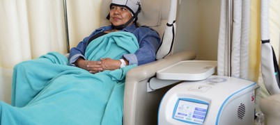 A patient in a chair using a scalp cooling system