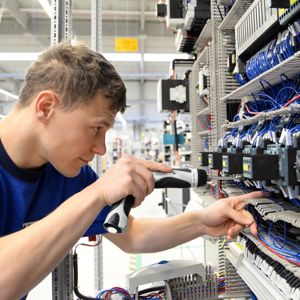 An Electrician Working On Electrical Components In A Factory Setting