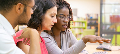 Three people sitting together at a computer learning some training together