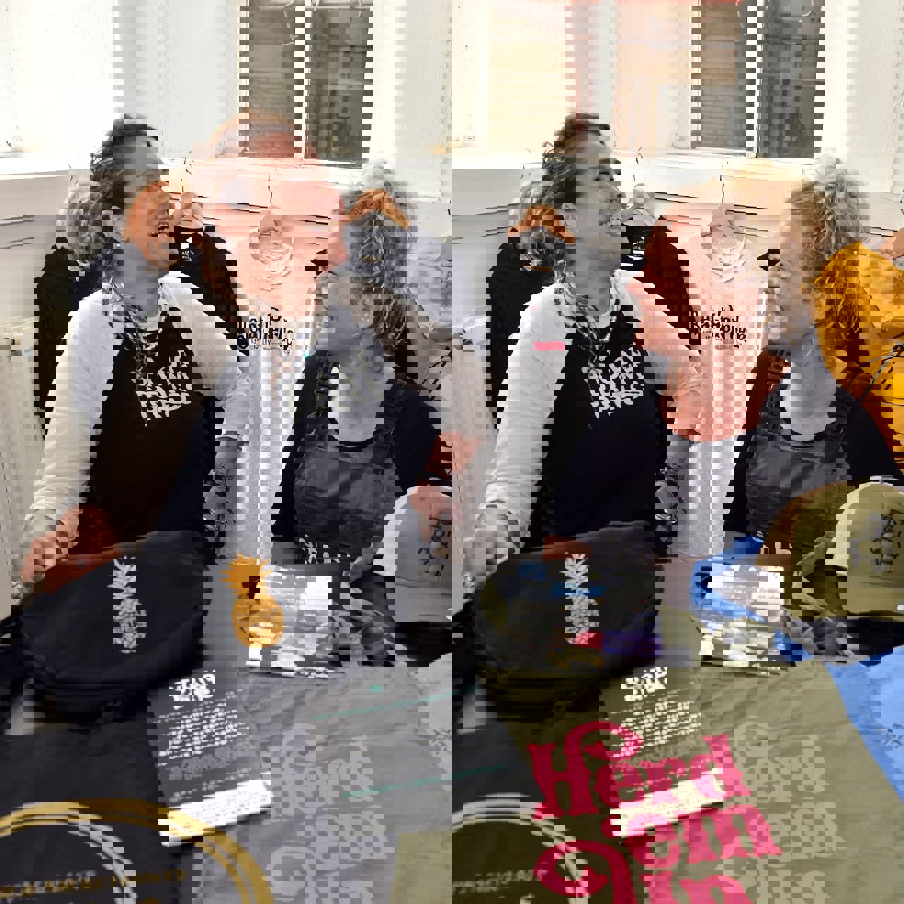 Two ladies laughing with a range of printed merchandise in front of them