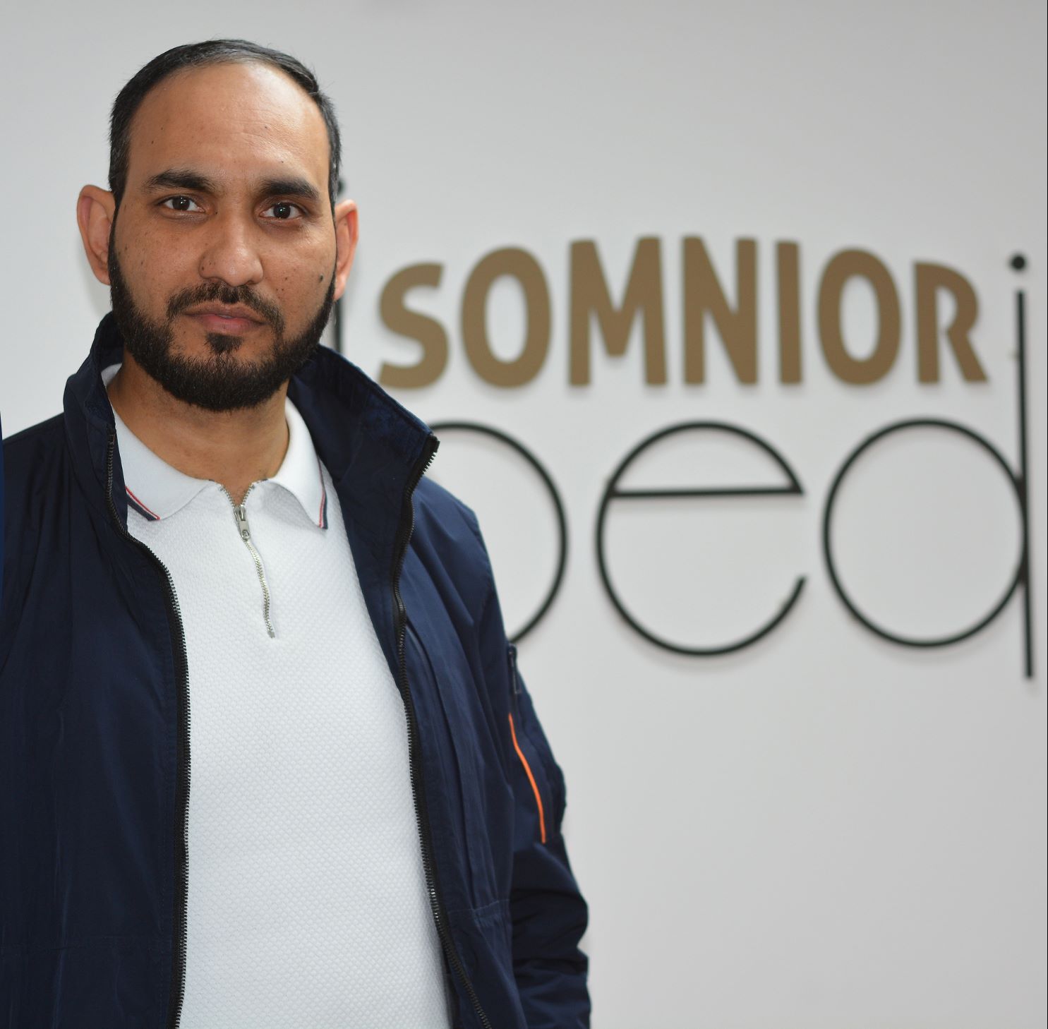 A man pictured in front of a Somnior Bed sign