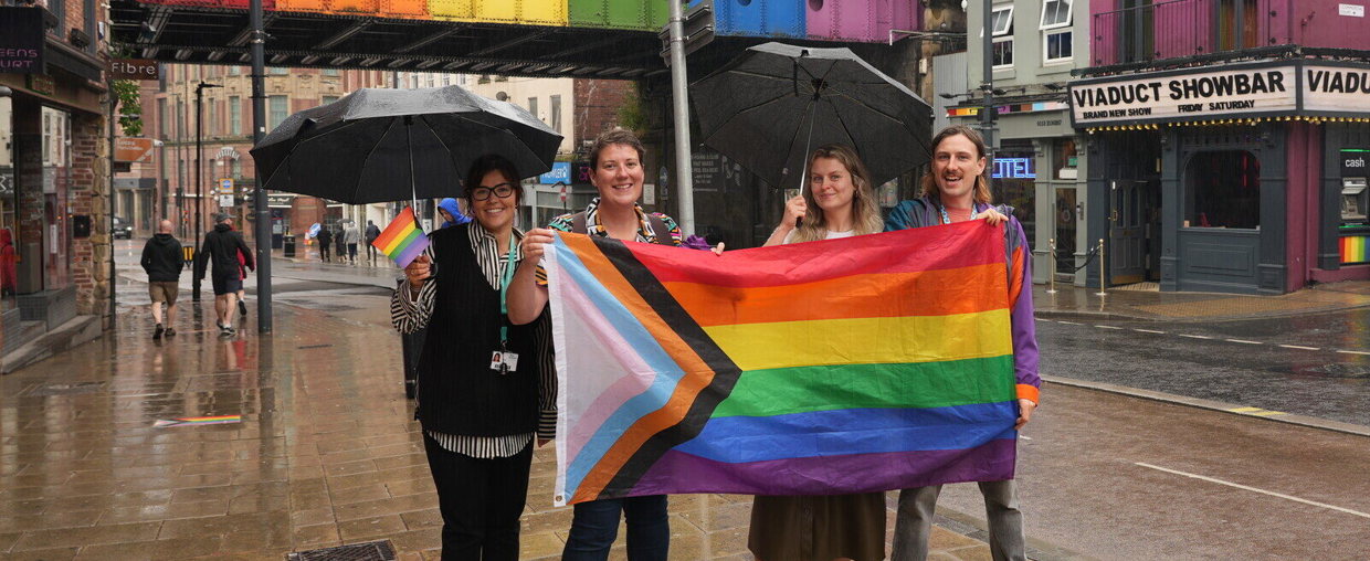 Combined Authority colleagues hold an LGBTQIA+ flag and wave flags, doing the Rainbow Plaques Trail
