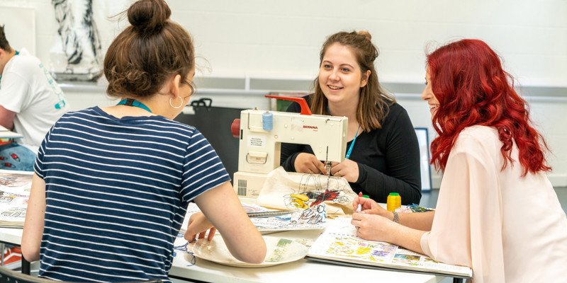 Students sewing together at table 