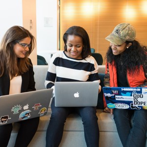 Group of students sitting together with laptops, smiling