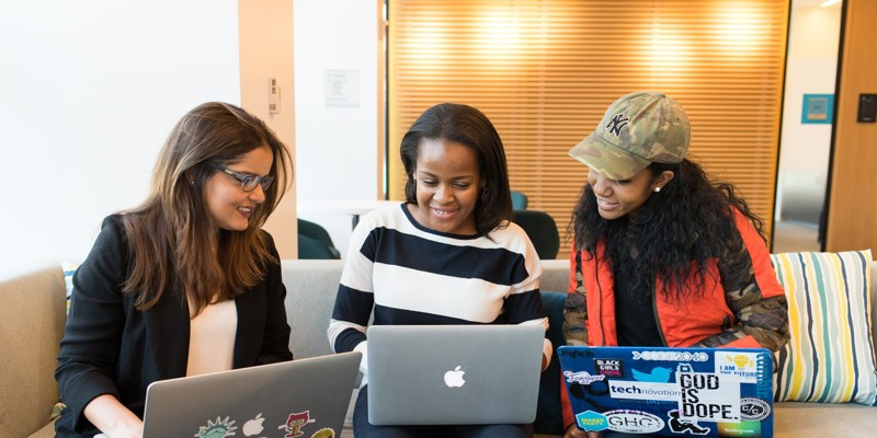 Group of students sitting together with laptops, smiling